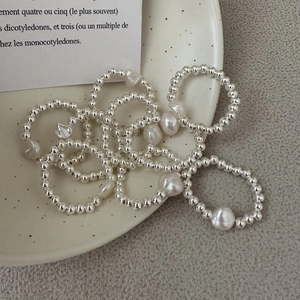 S925 silver beaded rings with baroque pearls arranged on a white ceramic plate