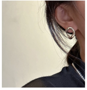 Gros plan d'une boucle d'oreille organique en argent minimaliste sur un mannequin