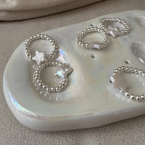 Close-up of S925 silver beaded rings featuring iridescent star-shaped pearl charms