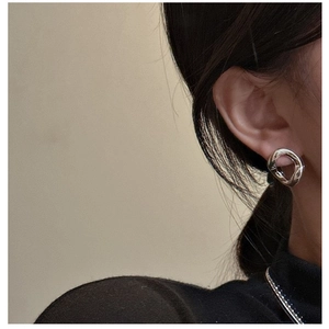 Vue latérale macro de boucles d'oreilles argentées irrégulières sur mannequin poli