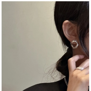 Détail de boucles d'oreilles créoles torsadées en argent S925 sur un mannequin femme