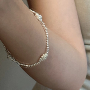 Détail d'un bracelet en argent S925 avec des perles blanches porté au poignet