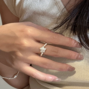 Detailed close-up of a silver beaded ring with a star charm on a model hand