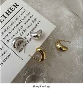 Macro shot of minimalist silver and gold pea-shaped stud earrings on glass background