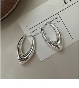Gros plan du poinçon S925 sur des boucles d'oreilles minimalistes polies en forme de U