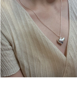 Close-up of S925 sterling silver heart pendant necklace on model with knit clothing