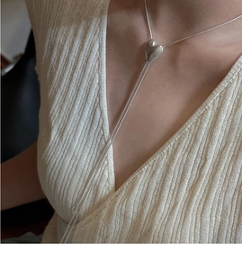 Dettaglio della collana a cuore in argento sterling S925 indossata su un maglione beige