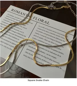 Macro detail of square snake chains in gold and silver finish on a decorative card