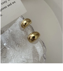Macro shot of polished gold-plated S925 sterling silver bean-shaped hoop earrings