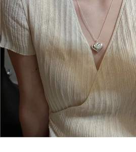 Close-up of minimalist S925 sterling silver hollow heart pendant on a thin beaded chain
