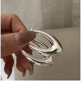 Gros plan sur des boucles d'oreilles créoles épaisses en argent S925 poli forme goutte