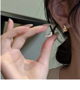 Detailed close-up of polished S925 sterling silver water drop earrings in gold and silver
