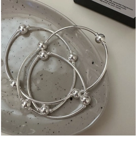 Detailed view of three-tier S925 silver beaded bracelets on a ceramic tray display