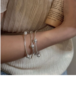 Detail of three-layer S925 sterling silver beaded bracelets layered on a model wrist