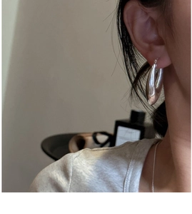Vue rapprochée de boucles d'oreilles minimalistes en argent portées par un mannequin