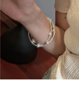 Detail of silver S925 multi-layered beaded bracelets worn on a wrist for a minimalist style
