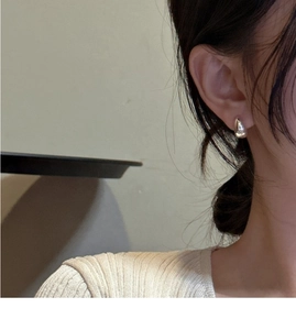 Close-up of polished S925 sterling silver teardrop earrings on a model ear