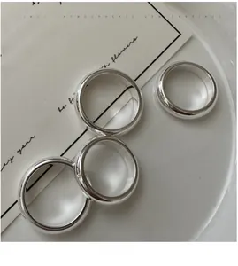 Lot de quatre bagues minimalistes en argent poli sur un plateau en céramique blanche