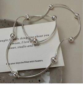 Macro detail of S925 sterling silver beaded bracelet with polished tubes on a ceramic plate
