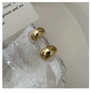 Detail of glossy gold teardrop stud earrings displayed on a textured ice tray