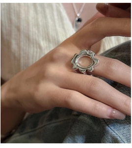 Detail view of a sterling silver plumeria ring with hollow petal design on a model hand