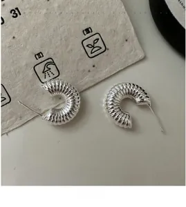 Macro detail of S925 sterling silver C-shaped earrings with fine spiral texture design
