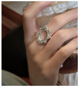 Detail of silver wavy floral ring worn by model holding a coffee cup in natural light