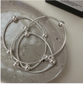 Detailed view of triple-layered S925 sterling silver beaded bracelets on ceramic tray