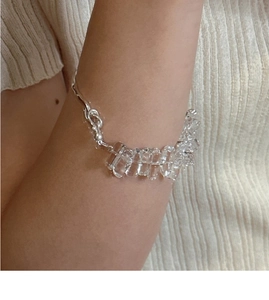 Détail du bracelet en argent S925 avec breloques en cristal clair sur manche en tricot