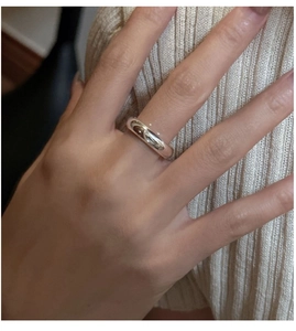 Vue rapprochée d'une bague minimaliste en argent poli portée sur un fond en tricot