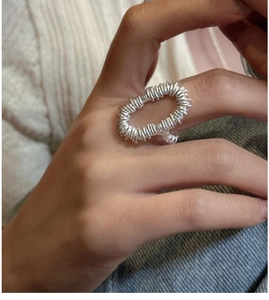Detailed view of silver woven wire texture on oval ring with hollow spiral craft design