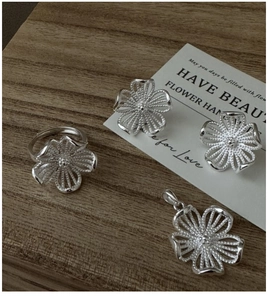 Détail de l'ensemble bijoux en argent S925 avec design de fleurs évidées sur bois sombre