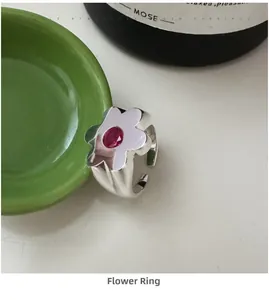 Macro detail of S925 silver flower ring featuring a polished finish and central red gemstone