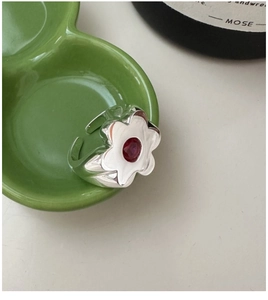 Detail of S925 silver flower ring with red gemstone set on a ceramic plate
