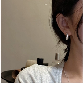 Close-up of silver-tone hollow hoop earrings with textured finish on a female model