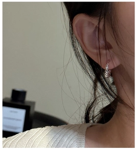 Close-up of S925 sterling silver croissant twist hoop earring worn on female model's ear