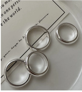 Bagues minimalistes en argent poli sur une assiette texturée avec une carte d'art