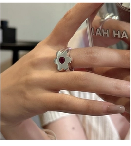 Detail of S925 sterling silver flower ring with a red gemstone on a finger