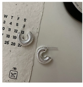 Macro detail of silver croissant hoop earrings with polished spiral textured surface