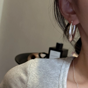 Boucles d'oreilles créoles S925 argent sterling portées par un modèle sous lumière douce
