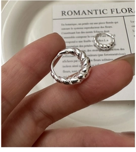 Macro shot of silver croissant-style hoop earrings with twisted texture held in hand