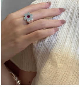 Detail of S925 sterling silver flower ring with a red gemstone on model's finger