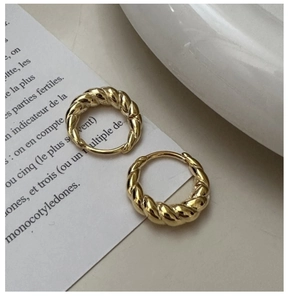 Detailed close-up of golden croissant hoop earrings with a twisted rope texture finish