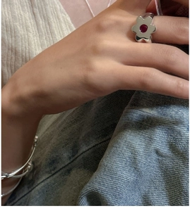 Close-up of S925 sterling silver flower ring with a red gemstone on a finger