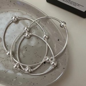 Three-piece set of S925 sterling silver minimalist bead bangles on a ceramic tray