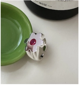 Close-up of S925 silver flower ring featuring a vibrant red center stone on green ceramic