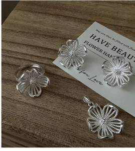 Detailansicht eines S925 Silber Blumen-Schmucksets mit Ring und Ohrringen auf Holz