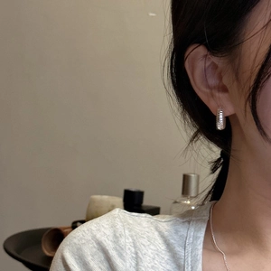 Elegant silver textured hoop earrings and delicate chain necklace on model
