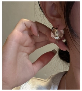 Close-up of minimalist S925 sterling silver oval hoop earring worn by a model