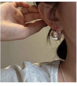 Close-up of a model wearing the polished oval sterling silver huggie earrings